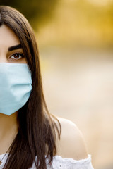 Portrait of a young girl in a medical sterile white mask staying safe from coronavirus. Prevent spread of covid-19 virus during quarantine. Girl looks forward to epidemic pandemia end.