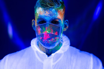 Portrait of man doctor in protective clothes in ultraviolet neon light during coronavirus pandemic. Epidemic, pandemic of coronavirus covid-19
