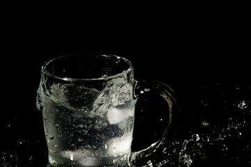 glass mug filled with water and ice with splash effect and black background