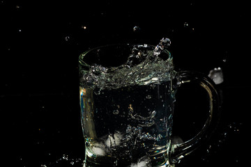 glass mug filled with water and ice with splash effect and black background