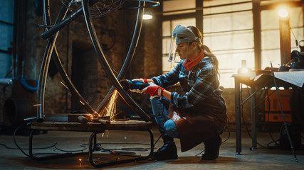 Young Contemporary Female Artist is Polishing a Metal Tube Sculpture with an Angle Grinder in a...