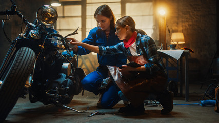 Two Young Beautiful Female are Discussing The Work Done on a Custom Bobber Motorcycle. Talented...