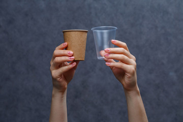 Zero waste concept. Wooden cutlery versus plastic cutlery. Eco-friendly disposable tableware made of bamboo wood and paper on a gray background. Caring for the environment. Recycling problem.