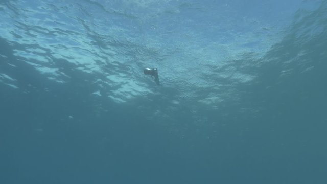 a gun thrown in sea coming from to the surface and sinking underwater slowly to the sandy bottom of sea