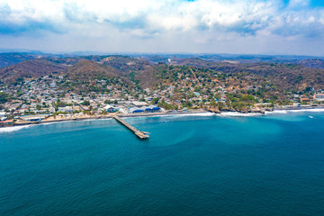 Aerial view over the coastal area on La Libertad beach in El Salvador, where you can see in its entirety its pier and the turquoise sea water.