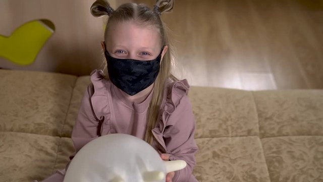 An inflatable balloon made of gloves, a girl in a masked house because of covid 19, sitting at home.