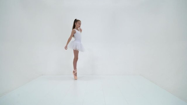 Cute little girl in a tutu and pointe shoes dancing in the studi
