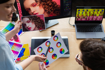 Professionals - photographer and retoucher. Retouching images on a graphics tablet. Teamwork in a...