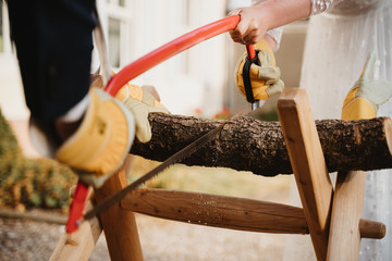 photo of a groom and a bride sawing a trunk