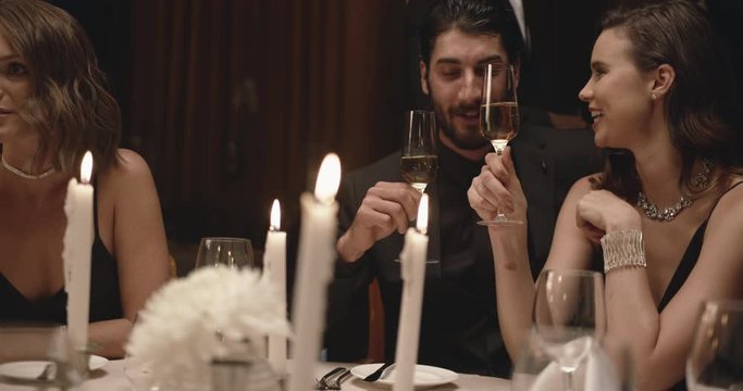 Young couple sitting at dining table with candles having wine. Loving man and woman at a gala dinner party.
