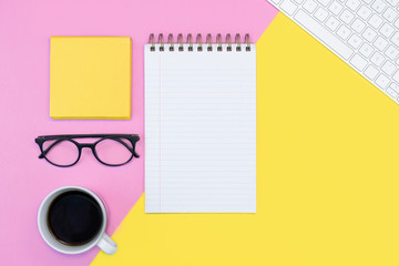pink and yellow working place or online education concept. note pad. writing. coffee, keyboard, glasses. spring concept.