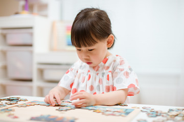 toddler girl playing wooden puzzle at home