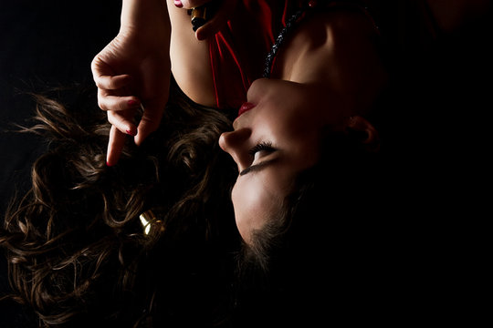 Close-up silhouette photo of a beautiful girl in the dark. Brunette girl with fragrant female perfumes. A young girl inhales the aroma of sprayed perfume on her wrists and neck - Powered by Adobe