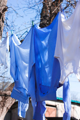 Blue shirts and white T-shirts dry on a rope in the street