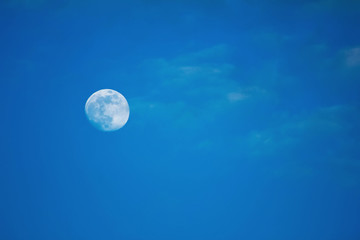 white full moon against blue sky, small clouds