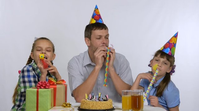 Girls and father joyfully blow whistles at the birthday party