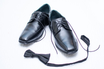 Black dress shoes for men and in front of the shoes a black bow tie.