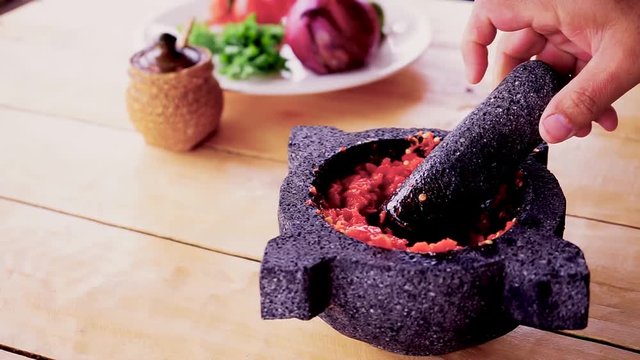 Using a morter to mash red hot chilli peppers