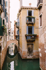Fototapeta na wymiar A narrow canal in Venice. Small canals between houses, a few meters. Beautiful little bridges between the streets.