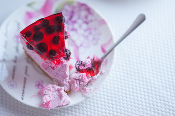 Currant cheesecake slice on a saucer with a spoon