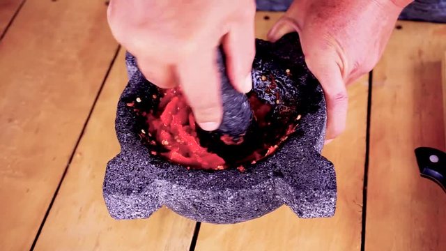 Using a morter to mash red hot chilli peppers