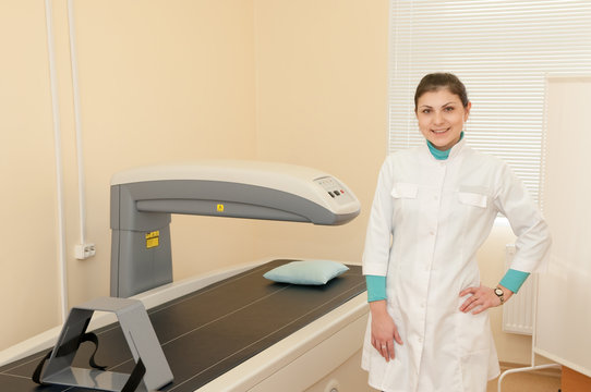 A female doctor stands next to a densitometer. Densitometry in the clinic. Medical equipment