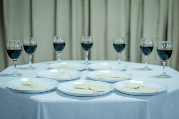 Ceremony table with white tablecloth with seven white plates with unleavened bread and in the background seven glasses of wine surrounding the table.