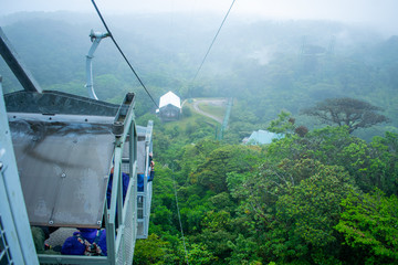Three gondolas going up the cloud forest of a reserve in Monteverde, a person is taking photos of the amazing view. In the back of the mountains is full of fog, Costa Rica © Daniel Umana 😎📸