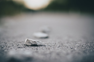 A sharp stone on a asphalt surface of a road. Detail photo of a sharp stone, concept of dangerous hazard for cyclist, roller skaters, skaters and even car tires, waiting to get a puncture