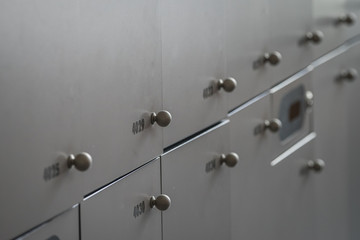 Close up of many lockers or metal or wooden lock boxes. Lockers with numbers, rfid codes and round knobs.