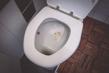 Cigarette butt in a toilet bowl. Female cigarette turned down in a bowl of a toilet. Dirty small toilet