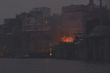 Manikarnika Ghat, seen from the water at nightfall with the fire of cremations.