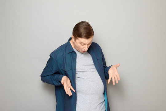 Portrait of man being surprised with his big stomach and fat body