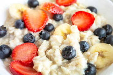 delicious Breakfast, oatmeal porridge with fruit slices strawberry, banana and blueberry close-up