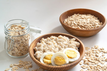close-up of ready-made oatmeal porridge for Breakfast with a boiled egg on a white background