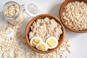dietary oatmeal porridge in a wooden dish with half-cooked eggs