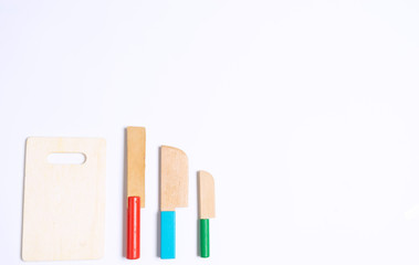 Sets of wooden knife toys. Bread knife, cleaver knife and paring knife as well as chopping board on top of white background