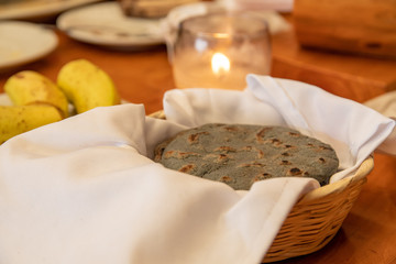 Basket of blue corn tortillas, with a candle in the background and another plate with three pieces of banana.