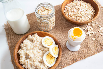 tablecloth with burlap on which the ingredients for cooking oatmeal, milk, boiled egg, ready porridge of oats are placed