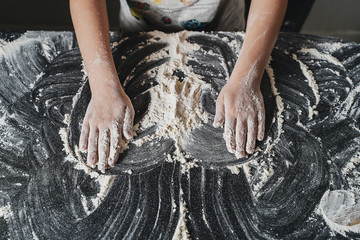 Children's hands help to cook flour in the kitchen