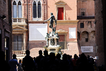 Group of people looks Neptune statue, famous symbol in Bologna - Italy