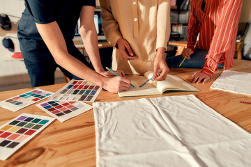 The power of us. Cropped shot of designers drawing sketches, while creating logo and design of...