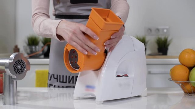Female hand sets stainless steel head in meat grinder for providing quality mince from meat. Electric mincer machine for minced meat per minute, make sausages, mashed berries, squeeze juice.