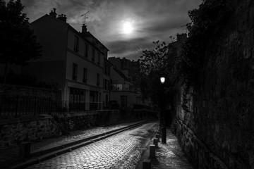 Paris, France - May 12, 2020: Small dark street on the Montmartre hill in Paris, a full moon night