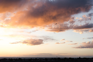 An airplane flying close to the ground during a sunset. 