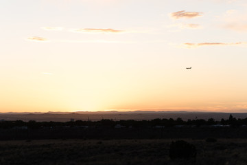 An airplane flying close to the ground during a sunset. 