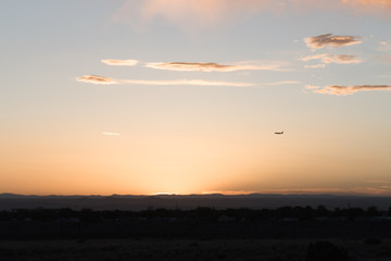 An airplane flying close to the ground during a sunset. 