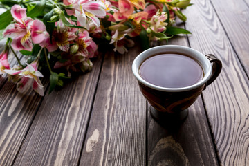 cup of tea and Alstroemeria on the wooden background. flowers on a brown background. copy text. beautiful bouquet.