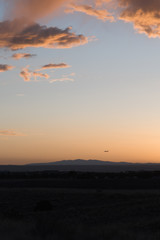 Obraz premium An airplane flying close to the ground during a sunset. 