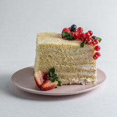 Slice of sponge cake with berries on white plate on white background. 